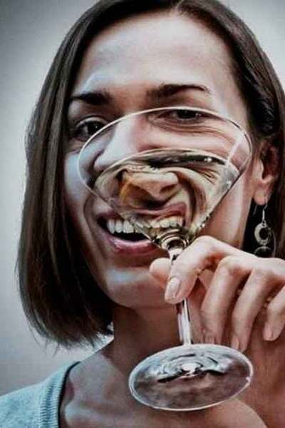 Женщина держит бокал с алкоголем в руке и улыбается