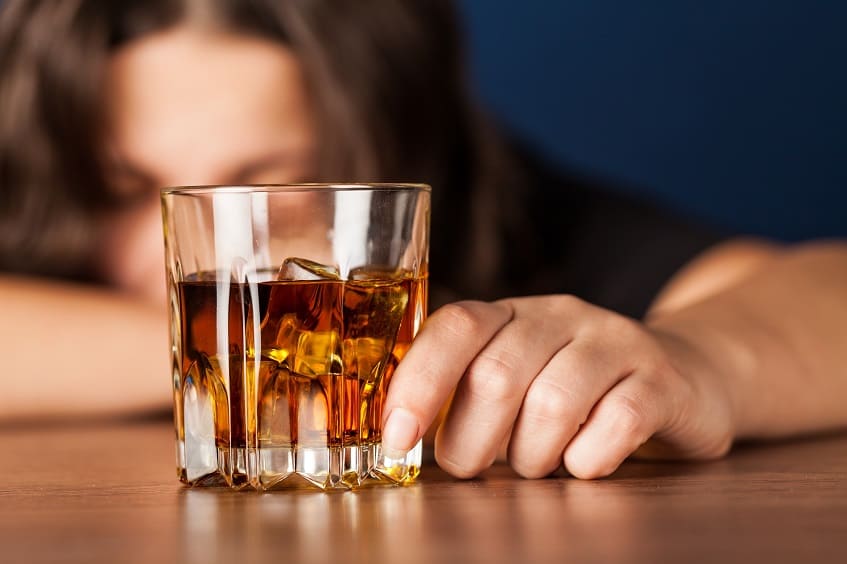 женщина смотрит на стакан с алкоголем
